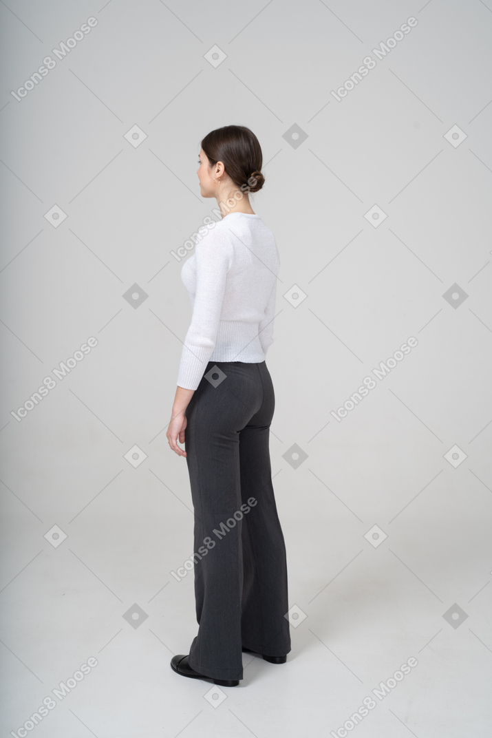Молодая женщина в белом свитере и черных брюках смотрит в сторону