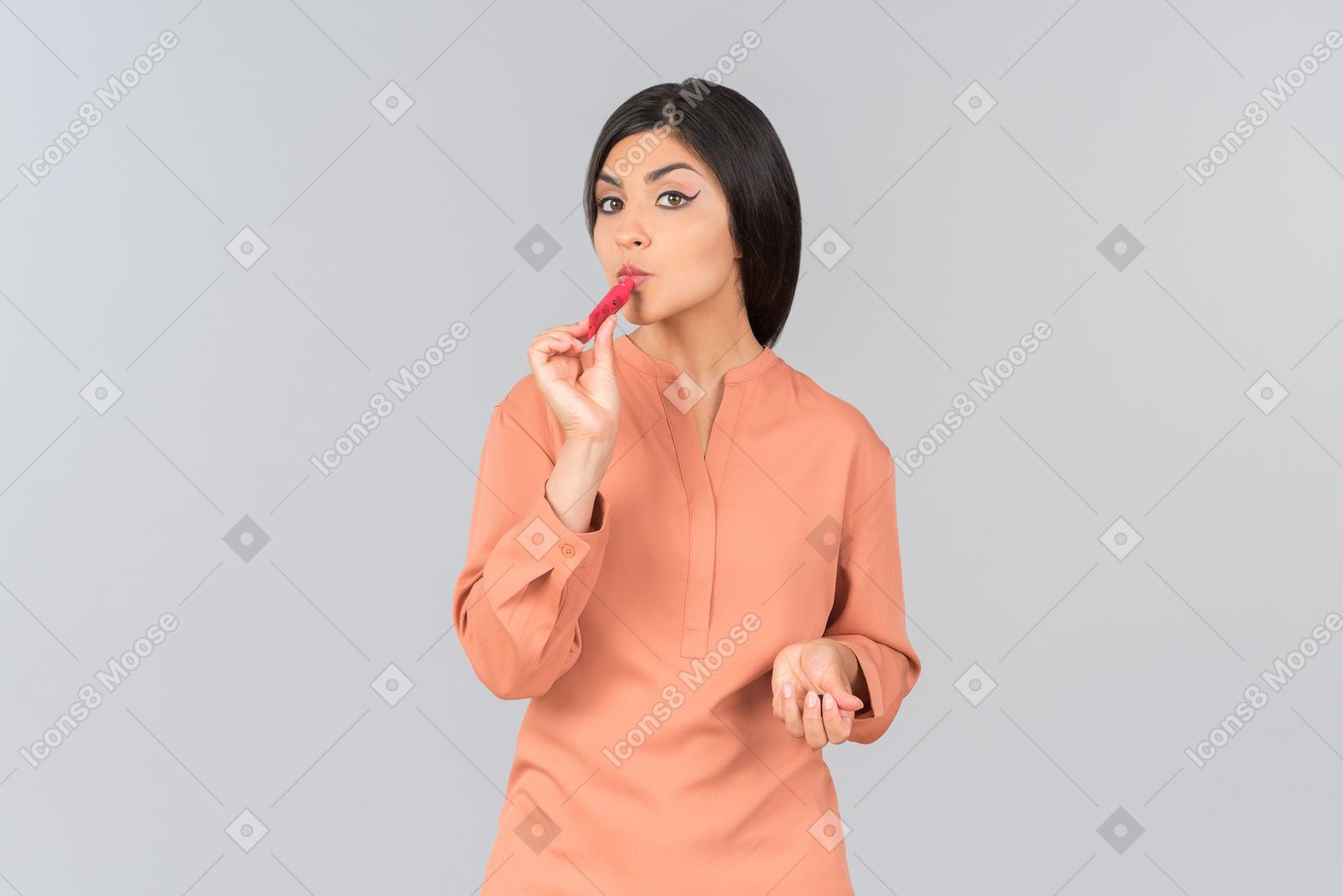 Mujer india en top naranja aplicando protector labial