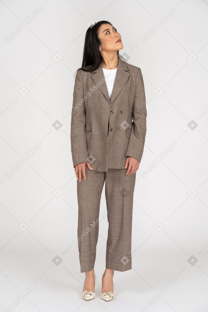 Front view of a young lady in brown business suit looking up while turning head