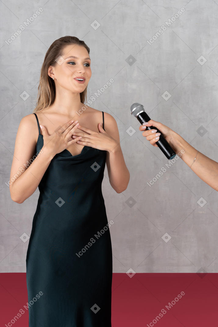 Vista frontal de uma jovem em vestido de noite dando uma entrevista