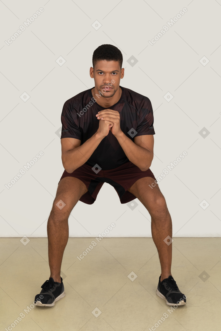 Young man in sports clothes squatting