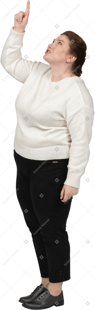 Vista laterale di una donna grassoccia in abiti casual che punta verso l'alto con un dito