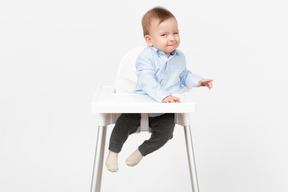 Adorable bebé niño sentado en una silla alta