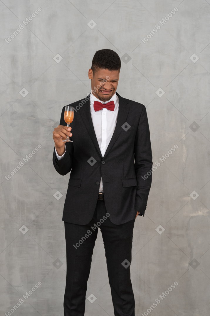 Young man with a champagne glass scrunching up his face
