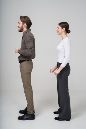 Vista lateral de um jovem casal encantado com roupas de escritório cerrando os punhos