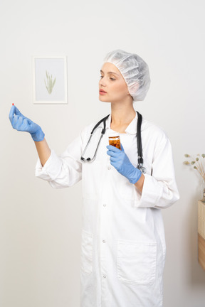 Three-quarter view of a young female doctor offering a pill