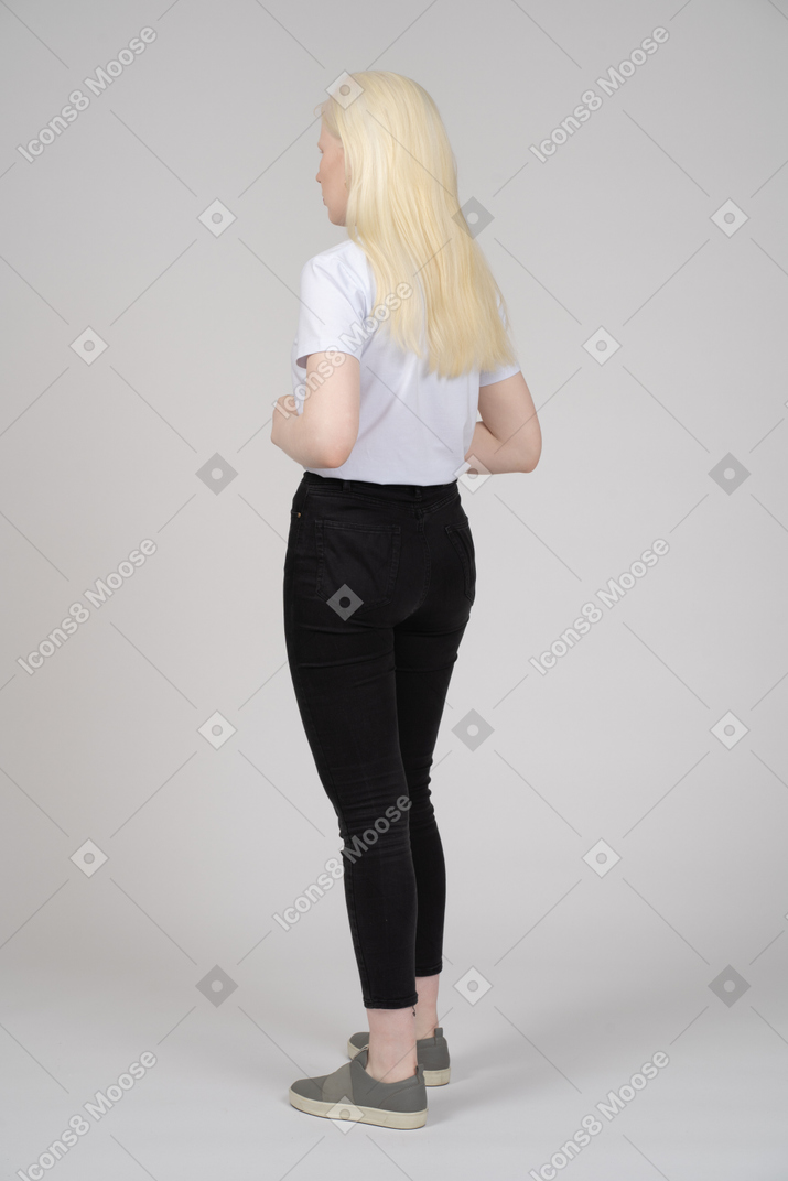 Back view of a standing young girl in casual clothes