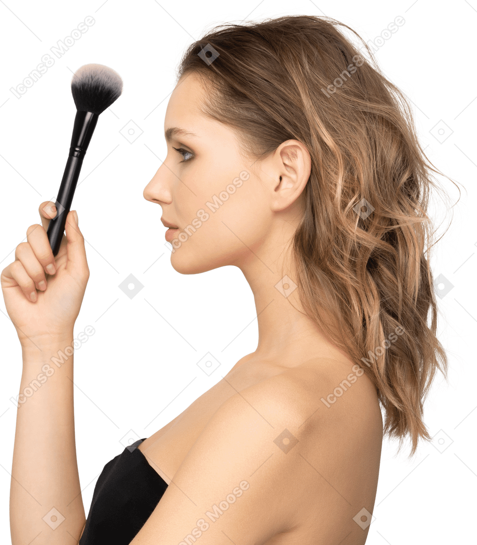 Side view of a sensual young woman holding a make-up brush