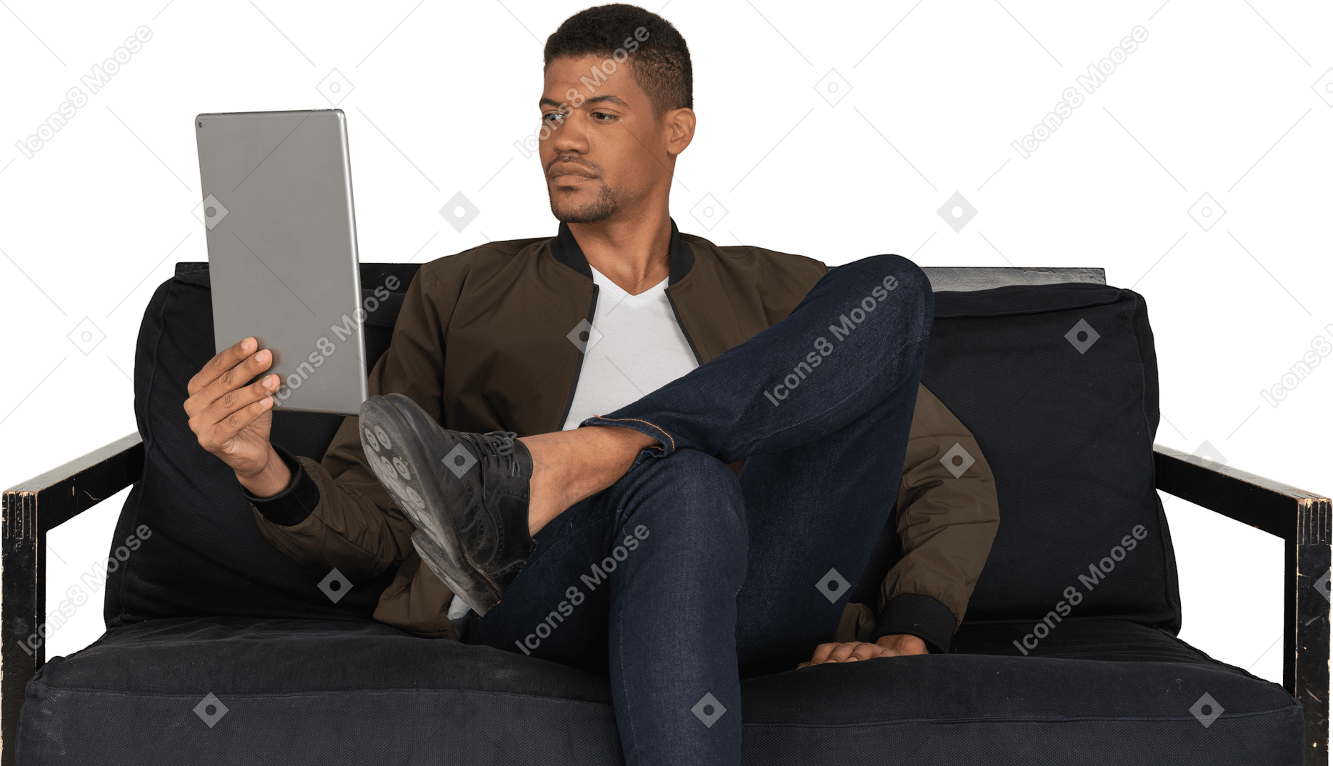 Vista frontal de um jovem entediado sentado em um sofá enquanto assiste ao tablet