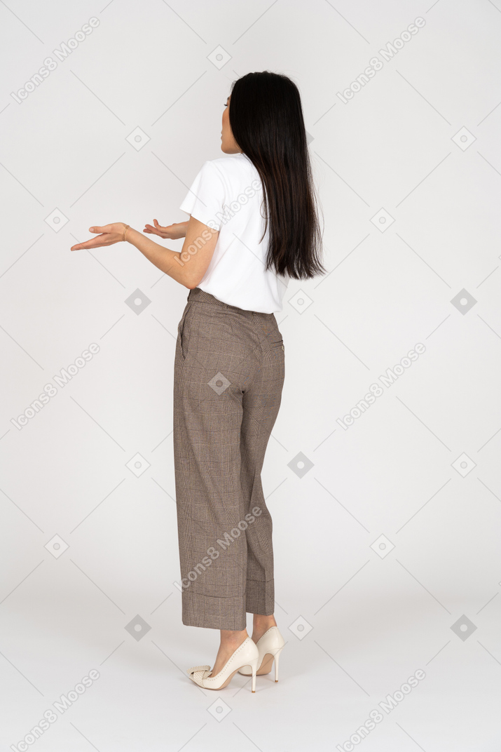 Vista laterale di una giovane donna chiedendo in calzoni e t-shirt alzando le mani