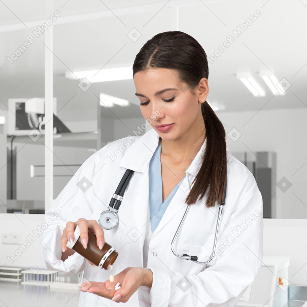 A female doctor pouring pills from a bottle on a hand