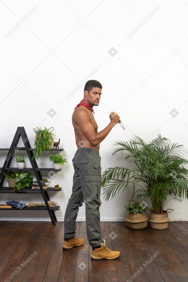 Side view of strong man with knife looking at camera