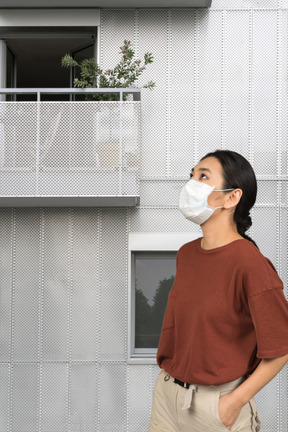 A woman wearing a face mask standing in front of a building