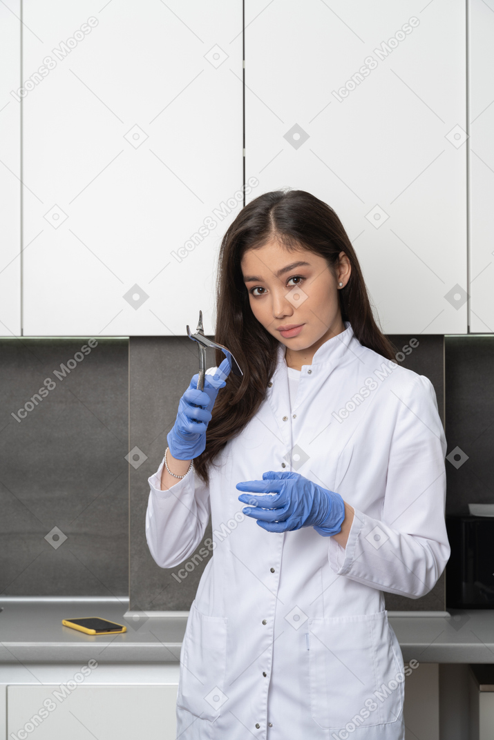 Front view of a female doctor holding her dental instrument and looking at camera