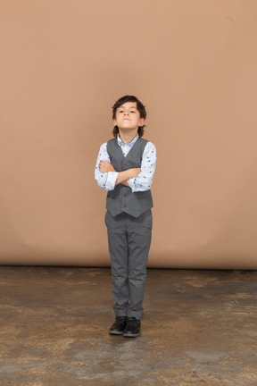 Front view of a boy in grey suit standing with crossed arms