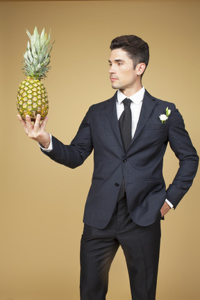 Novio en traje negro sosteniendo una piña y como felicitarlo