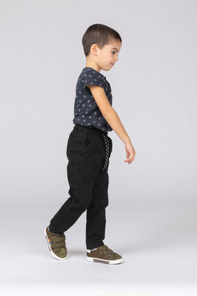 Vista lateral de um menino em roupas casuais caminhando