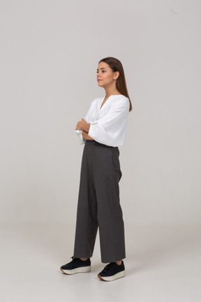 Three-quarter view of a thoughtful young lady in office clothing crossing arms