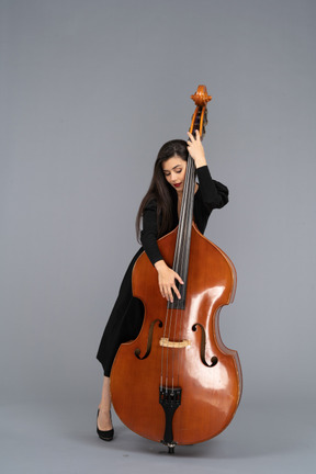 Front view of a pleased young woman embracing her double-bass