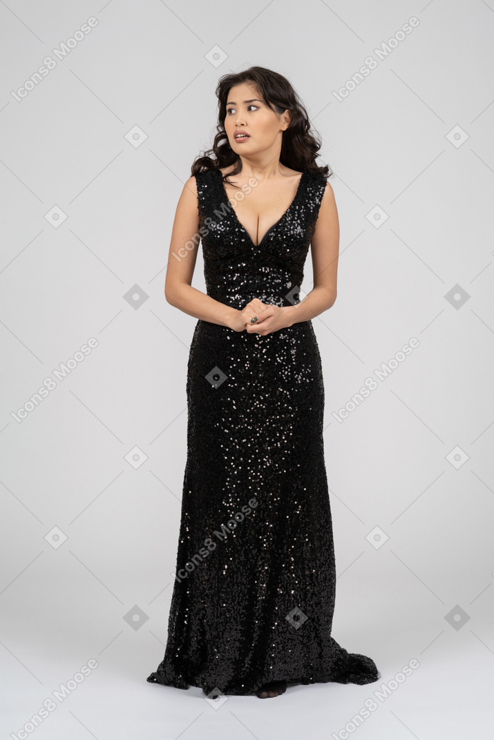 Beautiful woman in black evening dress looks a bit frightened
