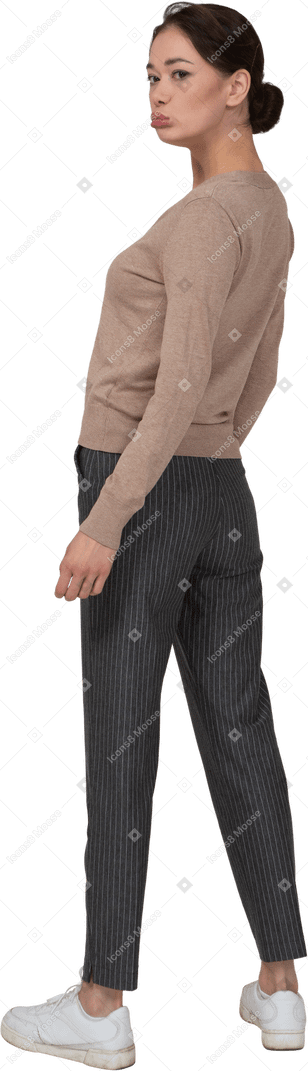 Vista posteriore di tre quarti di una giovane donna imbronciata in maglione e pantaloni che si allontana