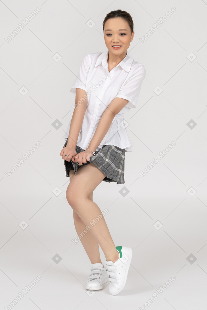 Sonriente joven asiática doblando su pierna y estirando sus manos