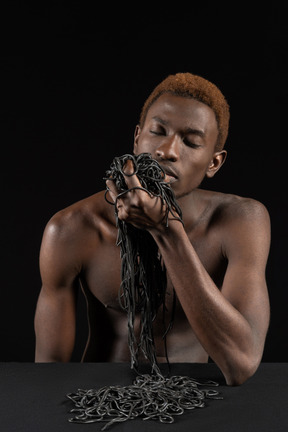 Front view of a young afro man holding an armful of pasta