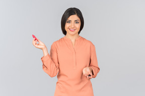 Индийская женщина в оранжевом топе держит бальзам для губ