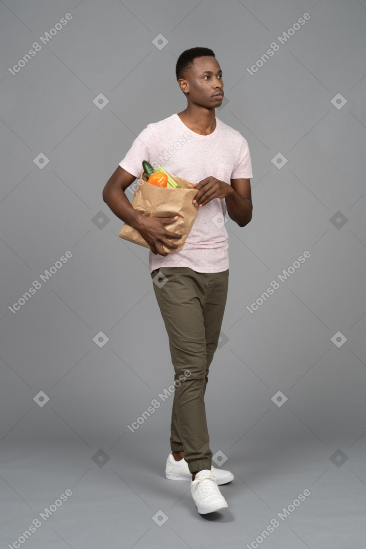 食料品の袋を運ぶ若い男