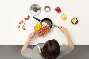 Una giovane donna che aggiunge le verdure a una casseruola