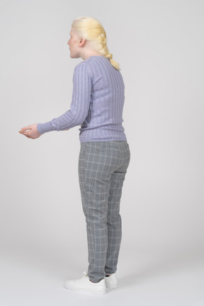 Vista posteriore di tre quarti di una donna in piedi con la mano tesa