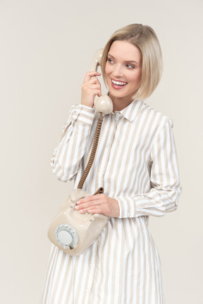 Giovane donna sorridente che parla sul vecchio telefono rotativo