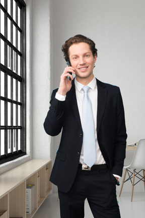 A man in a suit talking on a cell phone in an office