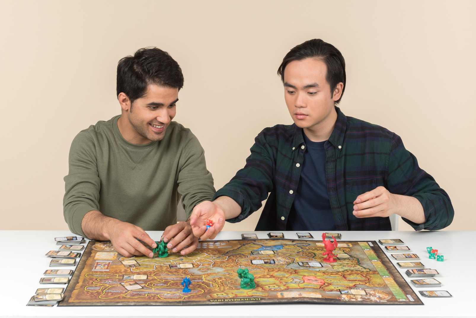 Interracial male friends sitting at the table and playing board game