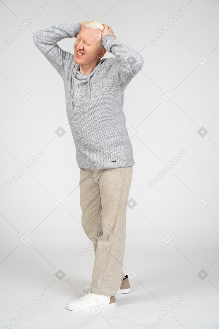 Mann mittleren alters mit händen am kopf, der an migräne leidet