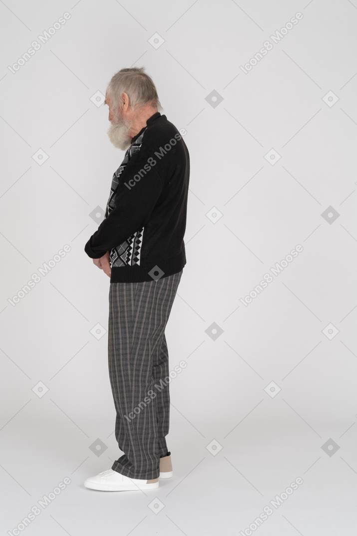 Side view of elderly man standing with clasped hands