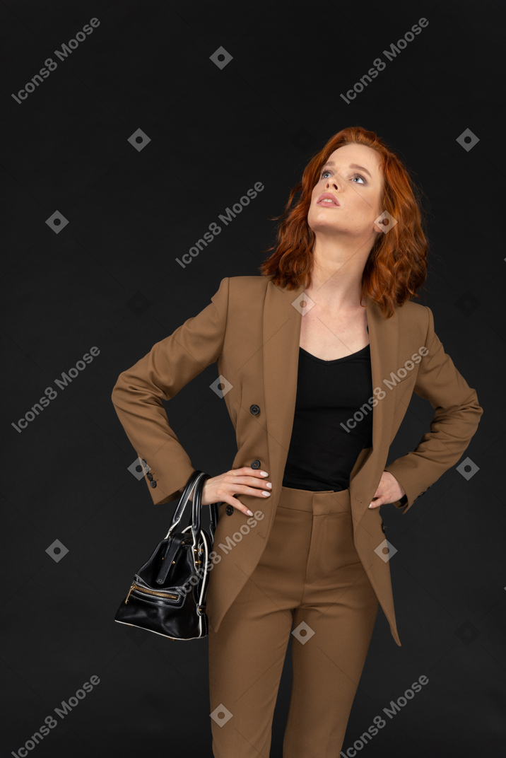 Молодая женщина в коричневом костюме смотрит вверх