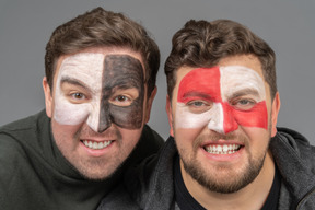 Front view of two male football fans with face art