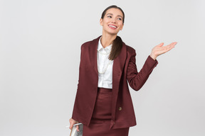 Attractive formally dressed woman with a clipboard pointing at something