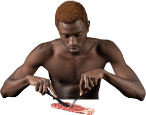 Front view of a withdrawn young afro man sitting near meat