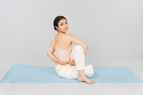 Jeune femme indienne assise sur un tapis de yoga