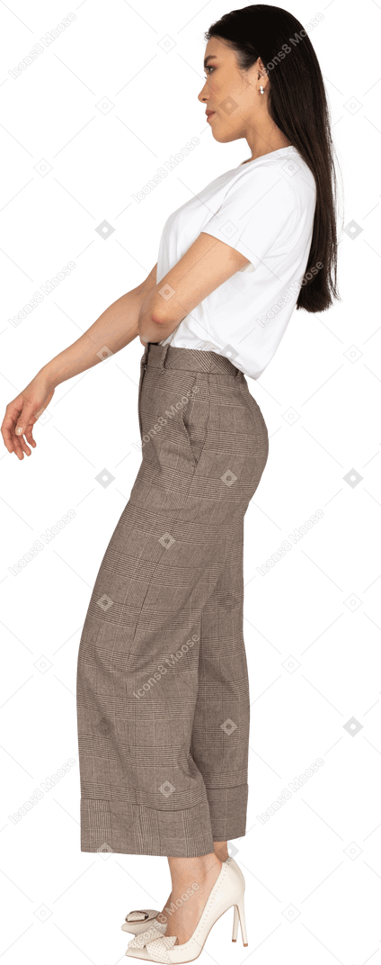 Vista laterale di una giovane donna premurosa in calzoni mettendo la mano sullo stomaco