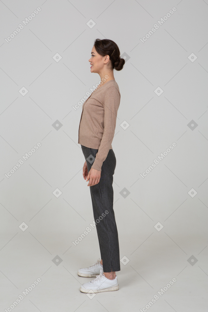 Vista laterale di una donna sorridente in pullover e pantaloni
