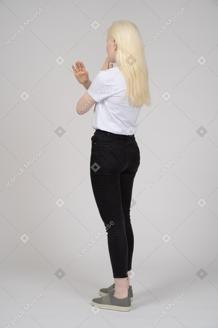 Vista posterior de una niña que no hace ninguna señal con los brazos cruzados