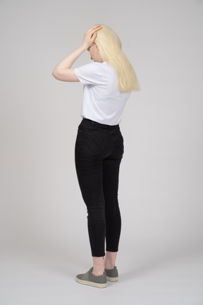 Back view of a young blonde girl touching her head