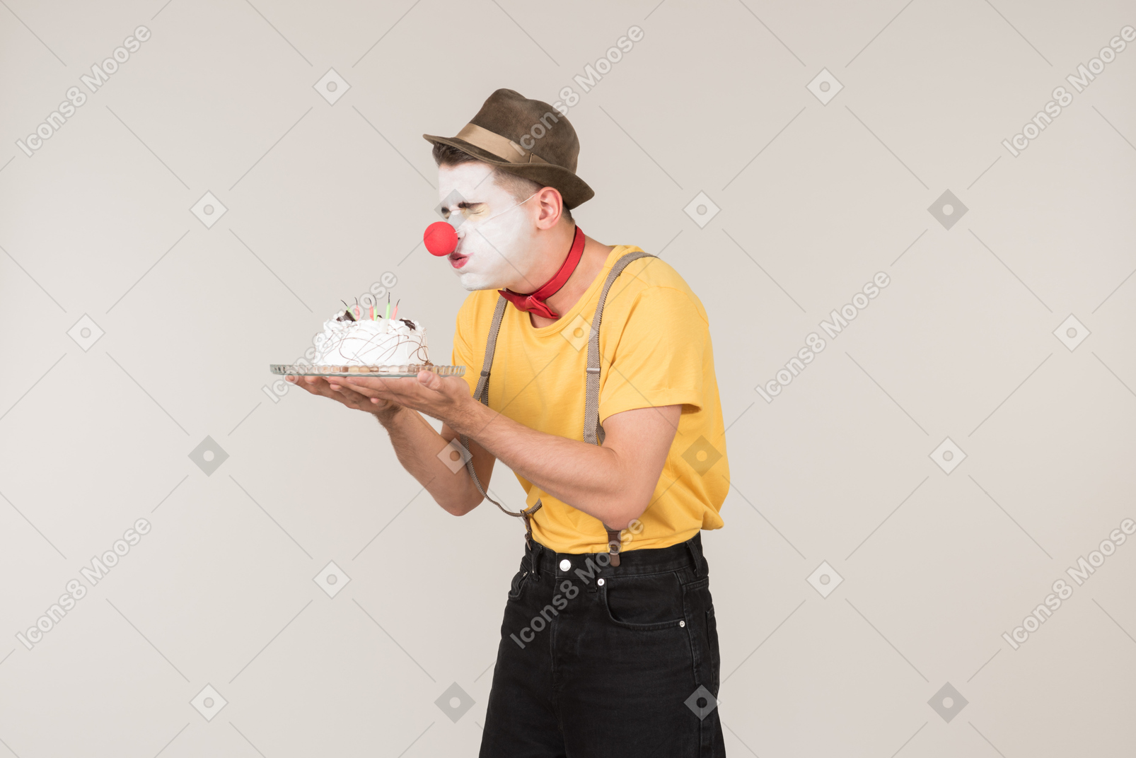 Male clown tasting a cake he's holding