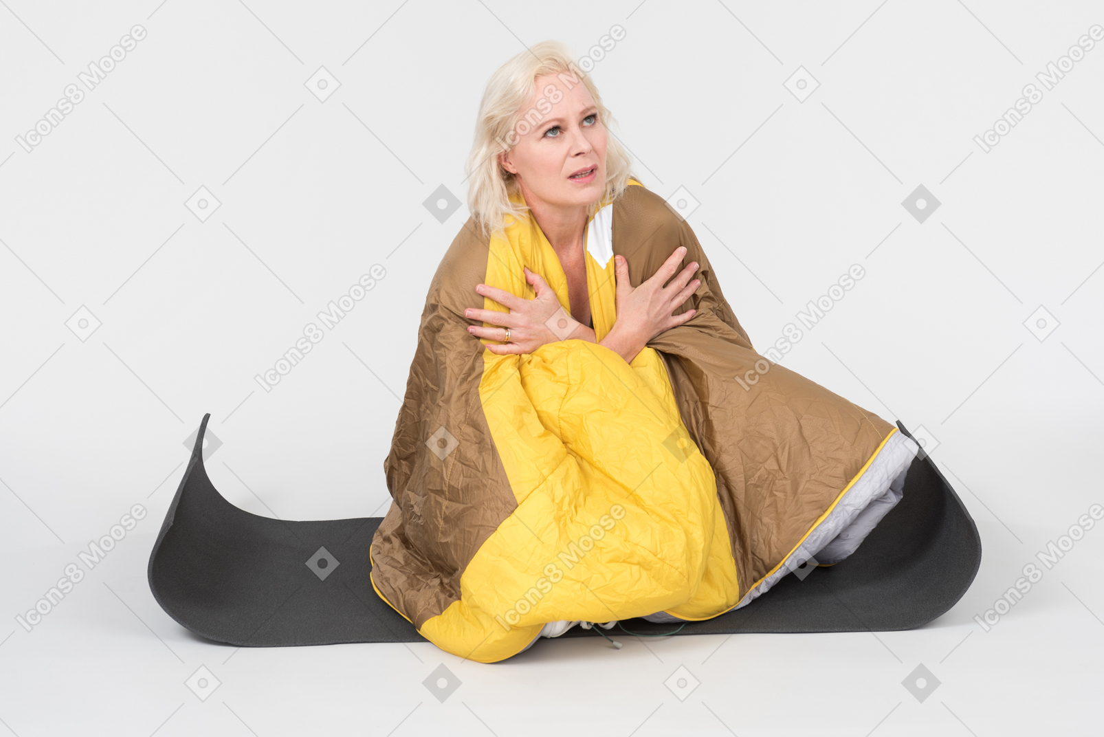 Mature woman sitting on yoga mat wrapped in blanket