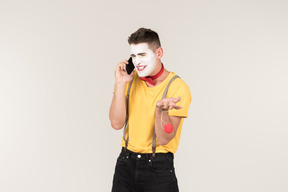 Troubled looking male clown talking on the phone