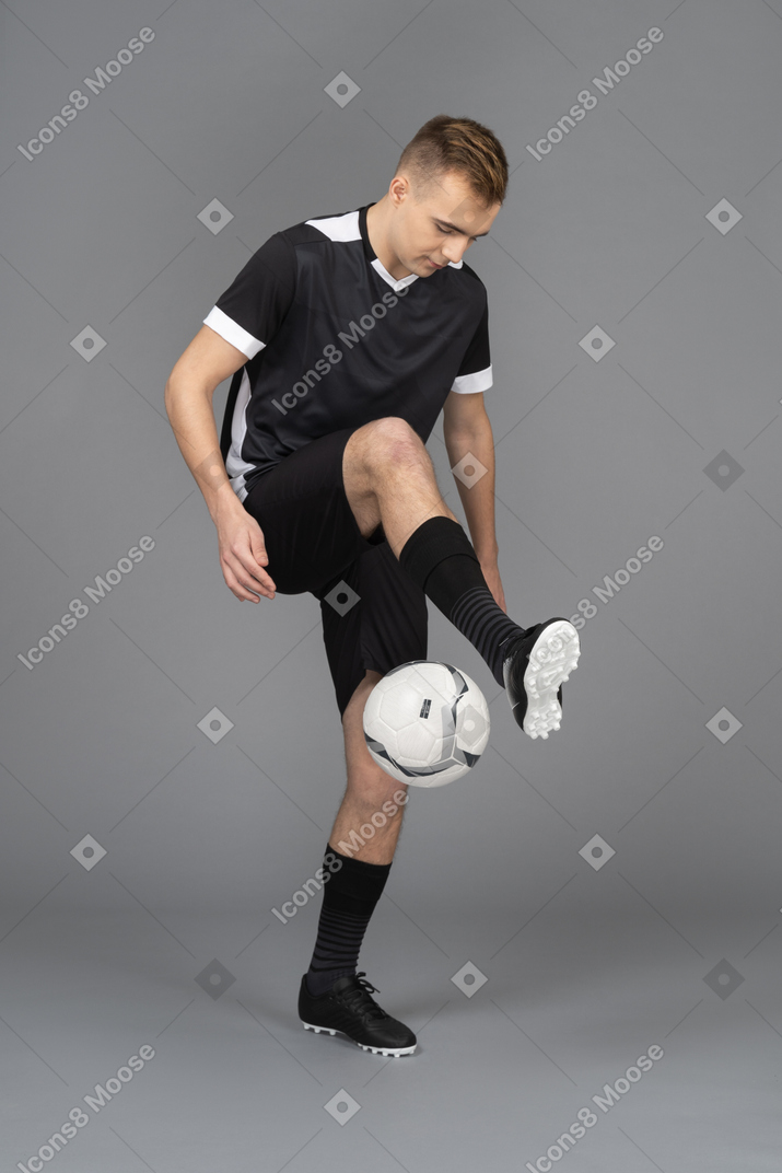 Three-quarter view of a male footballer player kicking a ball