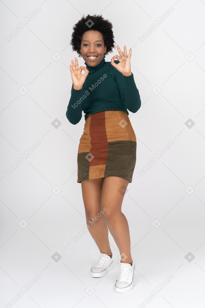 Niña afroamericana sonriente haciendo gesto bien con ambas manos